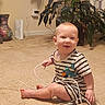Billy joined the competition — help win amazing prizes! baby, child, toddler, sitting, smiling, portrait, striped_clothing, onesie, barefoot, carpet, indoor, home, houseplant, vase, curtain, charging_cable, electronics, router, wall, floor