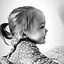 child, toddler, profile, smiling, hair, ponytail, dress, floral_pattern, bed, bedding, black_and_white, portrait, happy, cute, indoors, young_child, person, clothing, face, baby