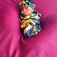 Esharie Owens joined the competition — help win amazing prizes! baby, sleeping, swaddled, headband, flower_pattern, sunflower, blanket, magenta, texture, cozy, infant, cute, portrait, resting, soft, peaceful, child, wrapped, indoor, newborn