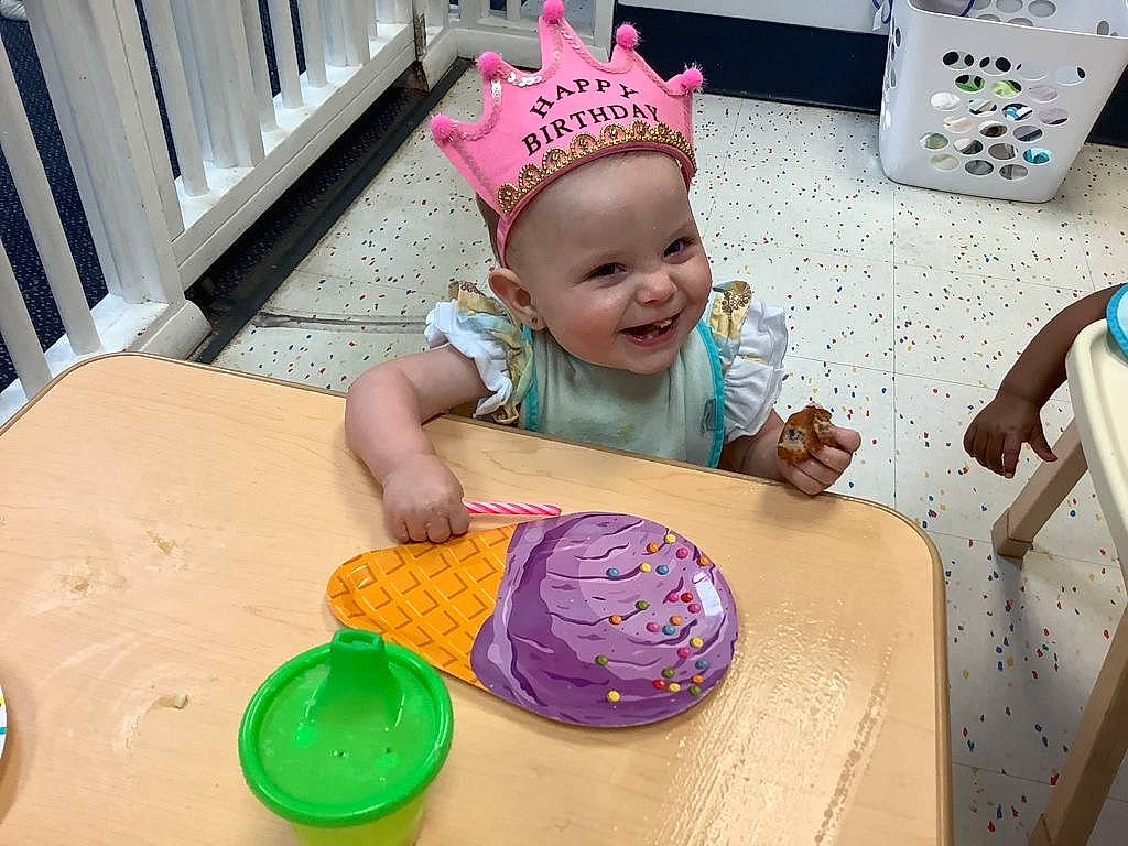 Mckenzie Rain is registered to the contest to win money with this photo: art, baby, baby_toddler_clothing, chair, child, circle, event, food, fun, happy, hat, headwear, icing, joy, leisure, person, pink, sharing, smile, sweetness