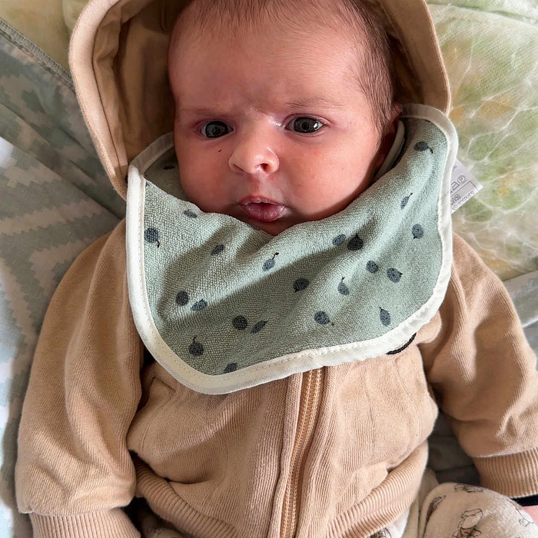 Lyvano a rejoint le concours — aidez-le/la à gagner de superbes lots ! baby, bib, blanket, child, clothing, cozy, cushion, cute, expression, face, hoodie, indoors, infant, lying_down, newborn, patterned_pants, person, socks, soft_texture, warm