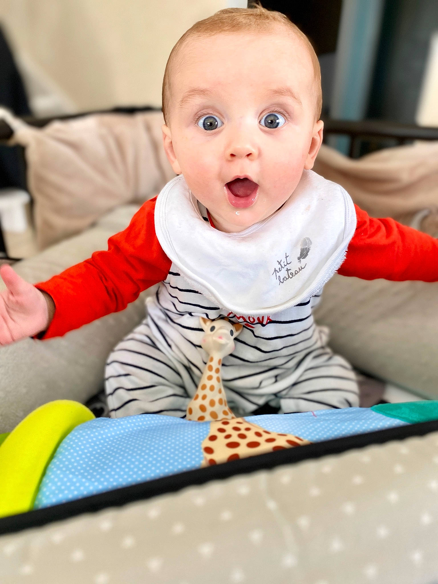 Charly a rejoint le concours — aidez-le/la à gagner de superbes lots ! baby, baby_toddler_clothing, cheek, child, comfort, finger, flooring, fun, happy, human_body, iris, person, product, room, sitting, skin, sleeve, smile, surprise, t_shirt
