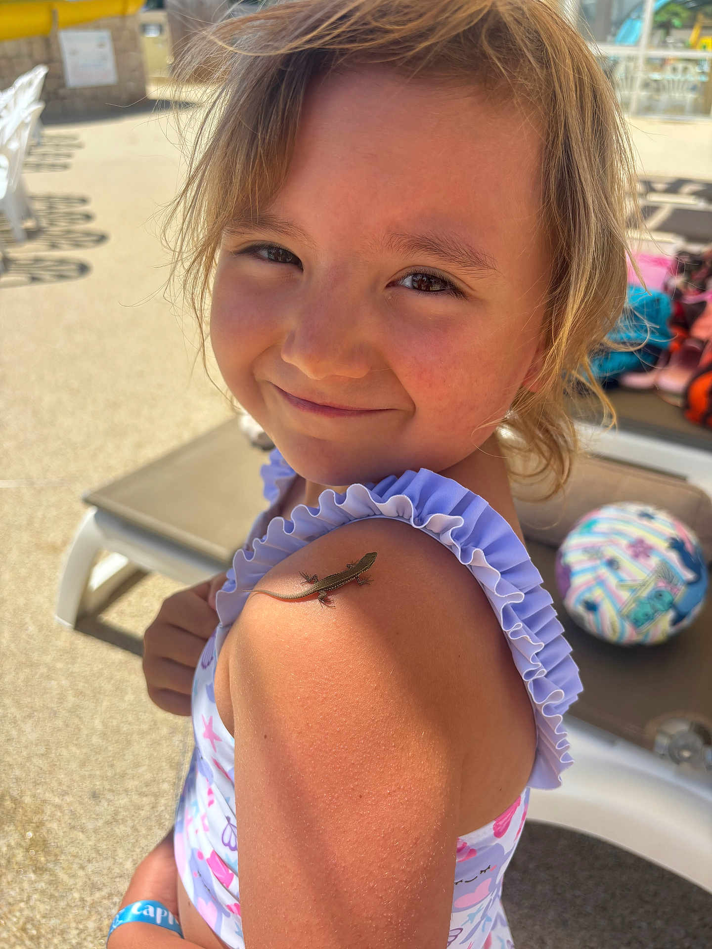 Lola participe au concours pour gagner de l'argent avec cette photo : child, smiling, lizard, shoulder, sunlight, outdoor, poolside, swimsuit, person, hair, face, summer, toy, playful, nature, animal, reptile, closeup, happy, skin