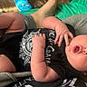 Dean joined the competition — help win amazing prizes! baby, infant, child, car_seat, lying_down, wide_eyed, surprised, open_mouth, portrait, black_clothing, graphic_shirt, hands, feet, adult_leg, turquoise_blanket, indoor, close_up, casual, seated, family