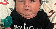 Dean is registered to the contest to win money with this photo: alice_in_chains, baby, band_shirt, black_shirt, blanket, child, close_up, dark_hair, face, hands, indoor, infant, lying_down, milestone_blanket, music, pacifier, patterned_blanket, portrait, rock, serious_expression