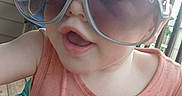 Heston is registered to the contest to win money with this photo: toddler, child, sunglasses, toy, colorful, smiling, porch, outdoor, baby, playtime, fashion, fun, cute, person, summer, sunlight, plastic, seat, casual, happy