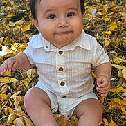 Marco is registered to the contest to win money with this photo: autumn, baby, child, dark_hair, daylight, face, fall, golden_leaves, grass, infant, leaves, nature, outdoor, photography, portrait, shirt, shorts, sitting, smiling, white_outfit