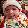 Mattéo a rejoint le concours — aidez-le/la à gagner de superbes lots ! adult, baby, background, bottle, cartoon_characters, christmas_bib, closeup, clothing, face, festive, holiday, indoor, infant, man, person, red, santa_hat, smiling, table, white
