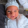 baby, infant, face, hat, white_clothing, smile, cute, newborn, person, portrait, indoors, cozy, soft_texture, star_pattern, headwear, skin, expression, warmth, comfort, closeup