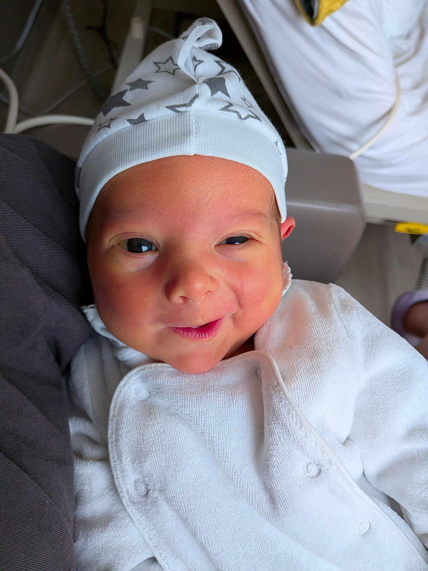 Mattéo a rejoint le concours — aidez-le/la à gagner de superbes lots ! baby, infant, face, hat, white_clothing, smile, cute, newborn, person, portrait, indoors, cozy, soft_texture, star_pattern, headwear, skin, expression, warmth, comfort, closeup