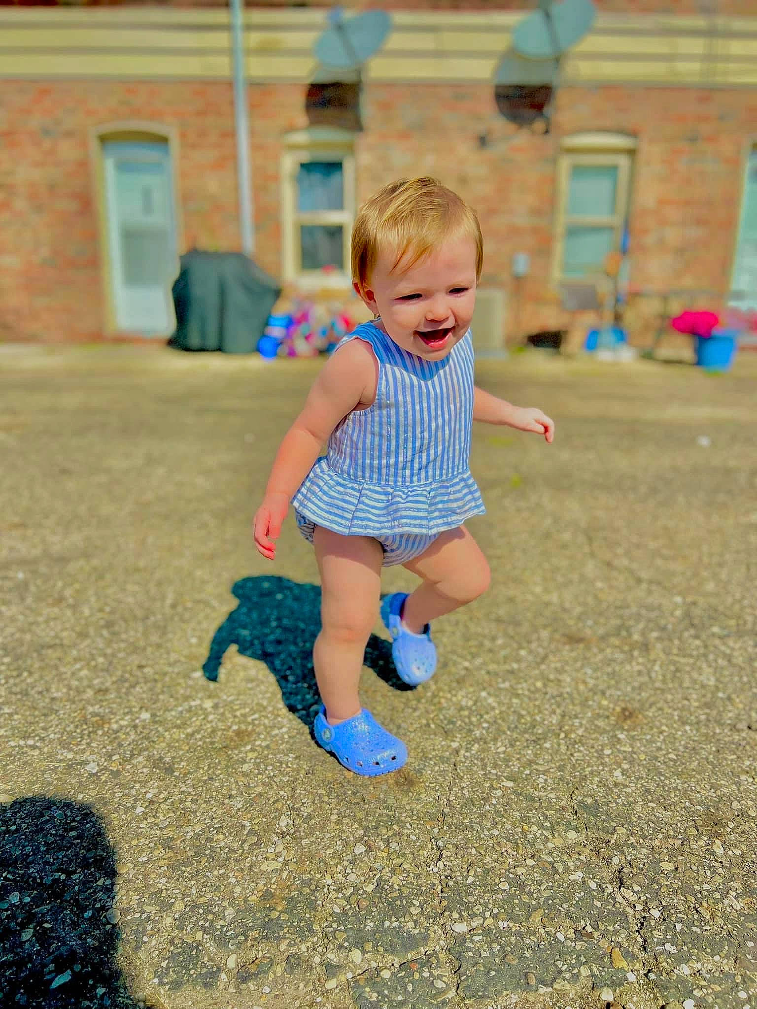 Gianna is registered to the contest to win money with this photo: asphalt, baby_toddler_clothing, child, city, door, electric_blue, flooring, foot, fun, grass, happy, human_leg, leisure, people_in_nature, person, recreation, road_surface, sand, summer, t_shirt