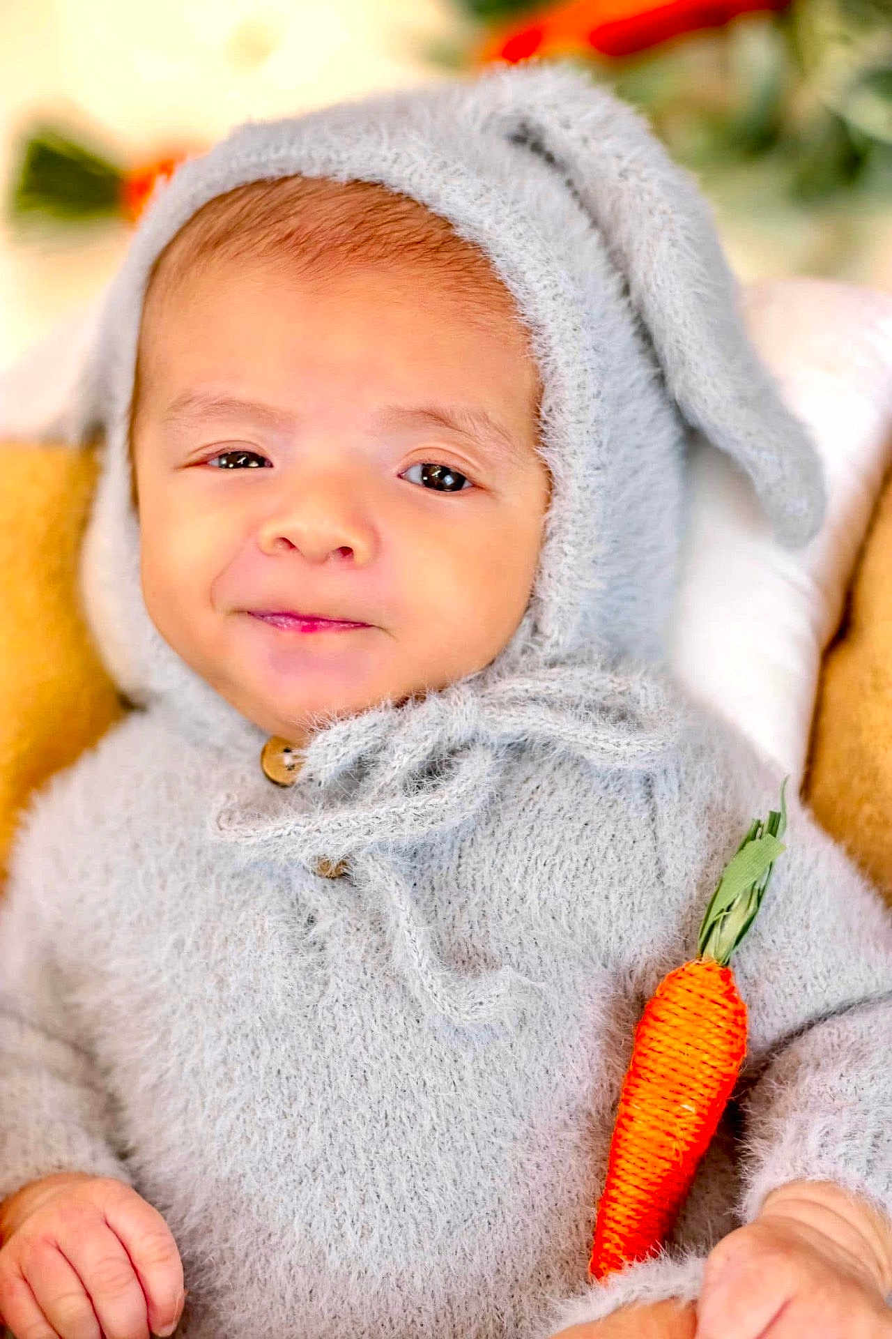 Isaac is registered to the contest to win money with this photo: baby, child, infant, bunny_costume, costume, carrot, cute, fuzzy, hood, knitwear, portrait, smile, soft_texture, toy, young_child, indoor, hand, face, eyes, adorable