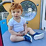 toddler, child, red_hair, white_shirt, blue_sneakers, marvel, playground, play_equipment, outdoor, sitting, curly_hair, window, thoughtful, casual_clothing, daylight, metal_structure, plastic_surface, fence, person, young_child