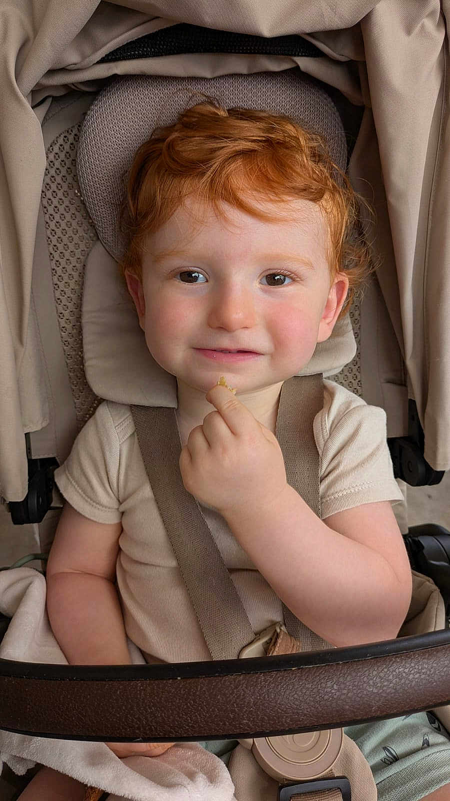 Sandro a rejoint le concours — aidez-le/la à gagner de superbes lots ! toddler, child, red_hair, stroller, seatbelt, beige, curly_hair, smile, hand, face, clothing, baby, indoor, cute, snack, headrest, person, young_child, portrait, seat