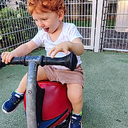 Sandro participe au concours pour gagner de l'argent avec cette photo : toddler, child, playground, spring_rocker, curly_hair, red_hair, white_shirt, shorts, sneakers, marvel, play, outdoor, fence, greenery, happy, tongue_out, fun, summer, daylight, toy