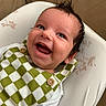baby, infant, child, smiling, laughing, portrait, close_up, face, eyes, hair, indoors, cushion, blanket, clothing, checkered_pattern, green, white,  버튼, cozy, happy
