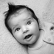 Eden joined the competition — help win amazing prizes! baby, child, infant, portrait, black_and_white, smiling, wide_eyed, lying_down, blanket, textured_fabric, indoors, close_up, face, eyes, hair, open_mouth, clothing, button, soft_lighting, photography