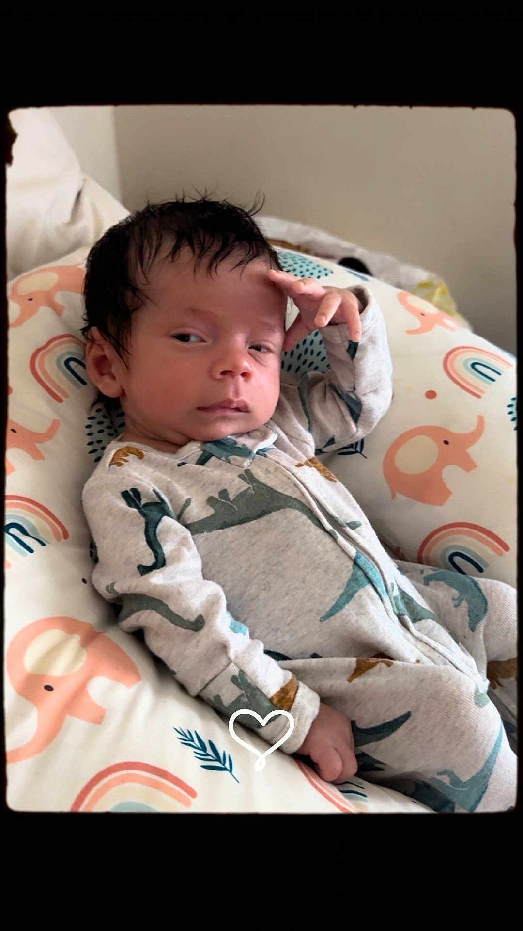 Halim is registered to the contest to win money with this photo: baby, infant, child, onesie, dinosaur_pattern, pillow, elephant_pattern, rainbow_pattern, sleepwear, indoors, portrait, cute, resting, hand_on_forehead, expression, young_child, cozy, soft_lighting, person, face