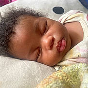 Keziah joined the competition — help win amazing prizes! baby, sleeping, curly_hair, blanket, onesie, close_up, peaceful, infant, face, soft_texture, nap, cute, child, resting, indoors, cozy, skin, mouth, eyelashes, head