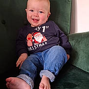 Arlo joined the competition — help win amazing prizes! baby, child, smiling, sweater, christmas, jeans, barefoot, green_chair, indoor, cute, happy, portrait, seated, infant, holiday, cozy, fashion, clothing, person, face