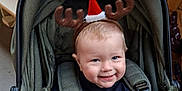 Arlo joined the competition — help win amazing prizes! baby, child, stroller, reindeer_antlers, santa_hat, holiday, christmas, festive, smiling, indoor, clothing, seasonal, cute, happy, retail, shopping, decorations, green, infant, headwear