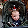 baby, child, stroller, reindeer_antlers, santa_hat, holiday, christmas, festive, smiling, indoor, clothing, seasonal, cute, happy, retail, shopping, decorations, green, infant, headwear