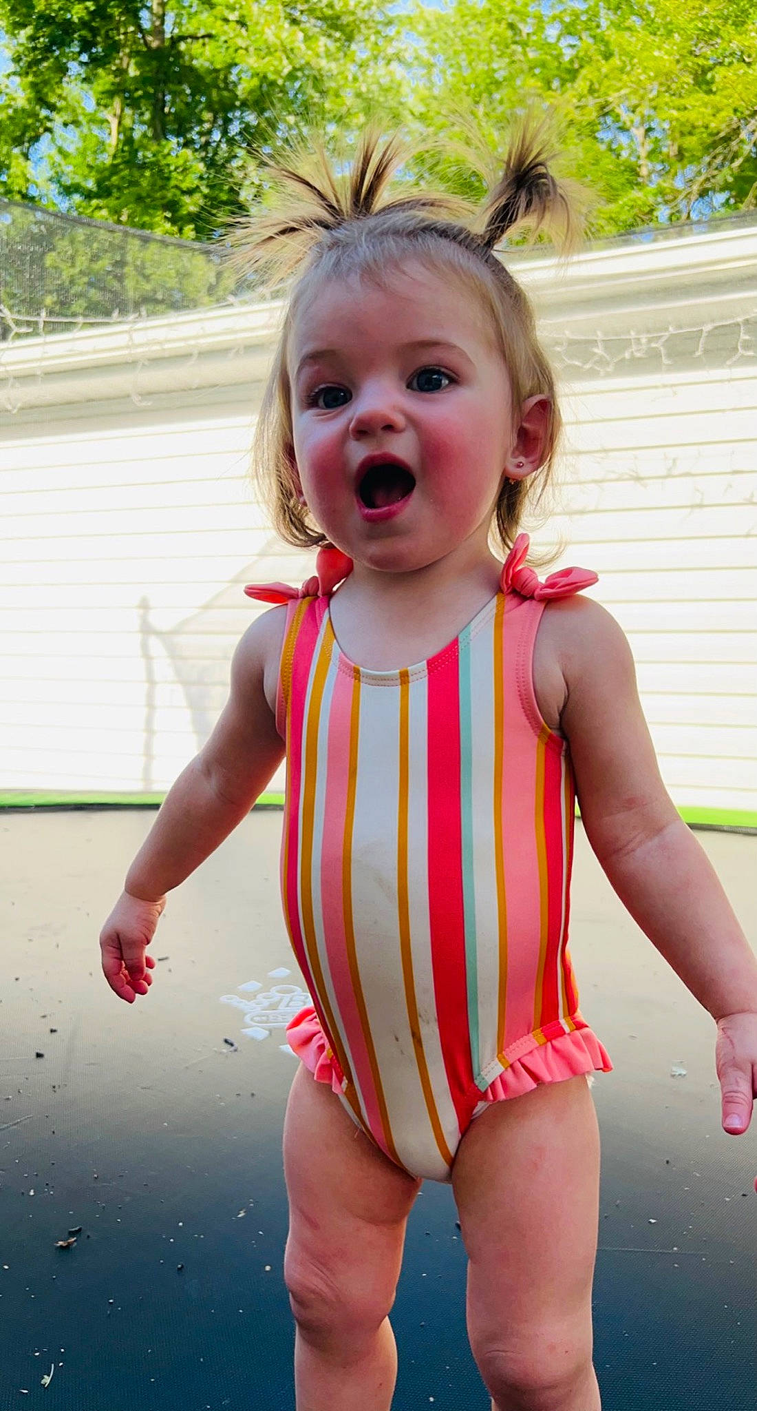 Melanie is registered to the contest to win money with this photo: arm, baby_toddler_clothing, dress, eye, face, fun, grass, hair, happy, head, lip, mouth, one_piece_swimsuit, person, pink, skin, sleeve, surprise, swimwear, thigh