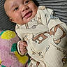 Kirk Jr is registered to the contest to win money with this photo: baby, smiling, infant, plush_toy, colorful, cozy_clothing, patterned_outfit, texture, gray_background, happy, cute, portrait, child, close_up, soft, hand, face, indoors, comfort, playful