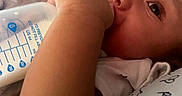 Kirk Jr is registered to the contest to win money with this photo: baby, milk_bottle, feeding, pillow, heart_pattern, close_up, infant, child, arm, face, eyes, comfort, blanket, cuddle, sleeping_area, cute, resting, skin, clothing, indoors