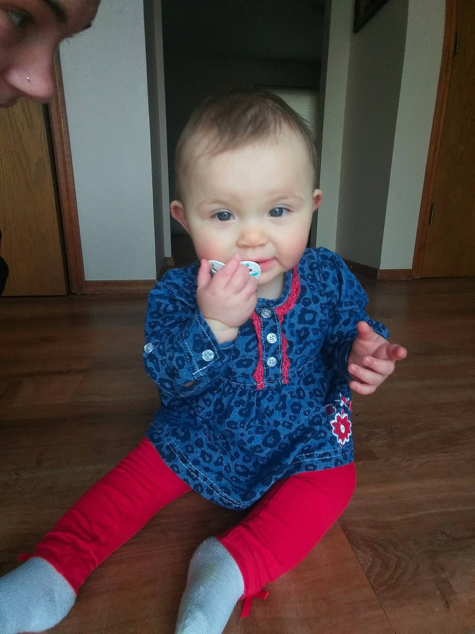 Alana is registered to the contest to win money with this photo: baby, cheek, child, electronic_device, eye, face, finger, floor, flooring, head, leg, lip, nose, person, sitting, skin, smile, standing, toddler, wood