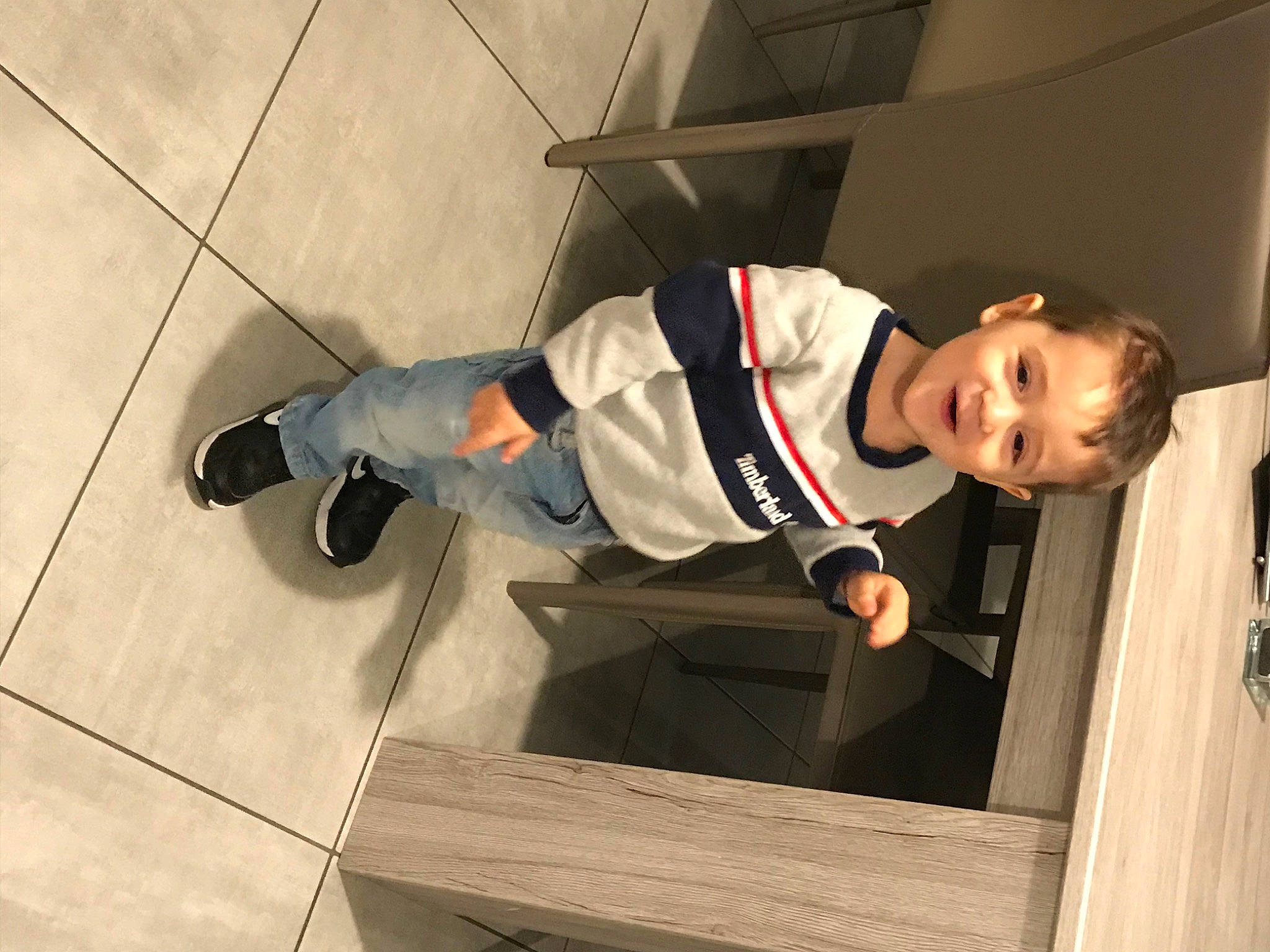 Tiago participe au concours pour gagner de l'argent avec cette photo : boot, cleanliness, concrete, flooring, hardwood, hat, joy, knee, outdoor_shoe, person, recreation, sleeve, smile, sneakers, sweatpant, t_shirt, toddler, varnish, walking_shoe, windbreaker