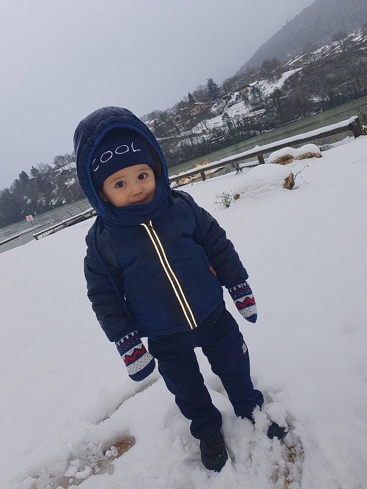 Tiago participe au concours pour gagner de l'argent avec cette photo : child, cloud, electric_blue, freezing, fun, glove, headwear, ice_cap, jacket, knit_cap, landscape, person, playing_in_the_snow, recreation, sky, smile, snow, toddler, tree, water