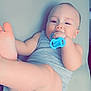 baby, infant, pacifier, grey_clothing, barefoot, lying_down, cute, child, skin, head, face, hand, foot, indoors, soft_surface, one_person, playful, relaxed, baby_girl_or_boy, sleepwear
