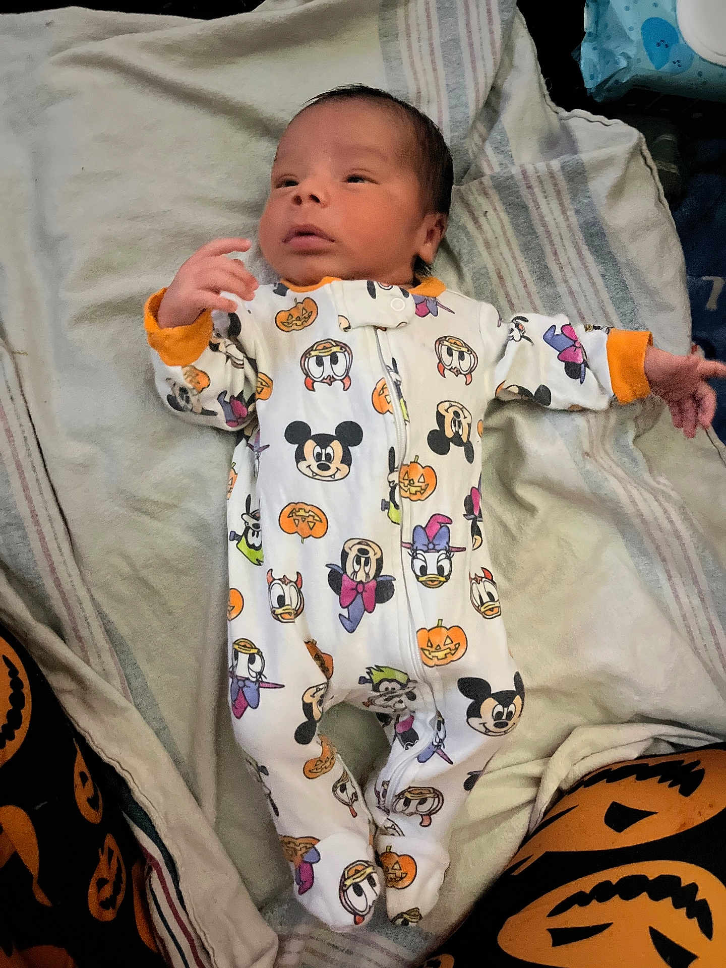 Zyion joined the competition — help win amazing prizes! baby, infant, onesie, cartoon_characters, halloween_theme, pumpkin, blanket, striped_blanket, lying_down, clothing, cute, child, footed_pajamas, orange_cuffs, indoor, person, face, head, newborn, festive