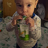 Zy'Aire is registered to the contest to win money with this photo: toddler, child, baby_food, pouch, indoor, blanket, toy, cabinet, curly_hair, clothing, person, floor, car_print, foot, hand, face, eyes, expression, standing, home