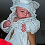 Hudson is registered to the contest to win money with this photo: baby, child, person, fluffy_clothing, bathrobe, elephant_ears, hand, arm, watch, red_shirt, indoor, curious, skin, face, wide_eyes, soft_texture, cute, portrait, infant, holding