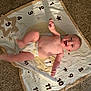 baby, diaper, blanket, numbers, stars, carpet, smile, face, child, infant, happy, playful, lying_down, kicking, cute, indoors, young, skin, head, person
