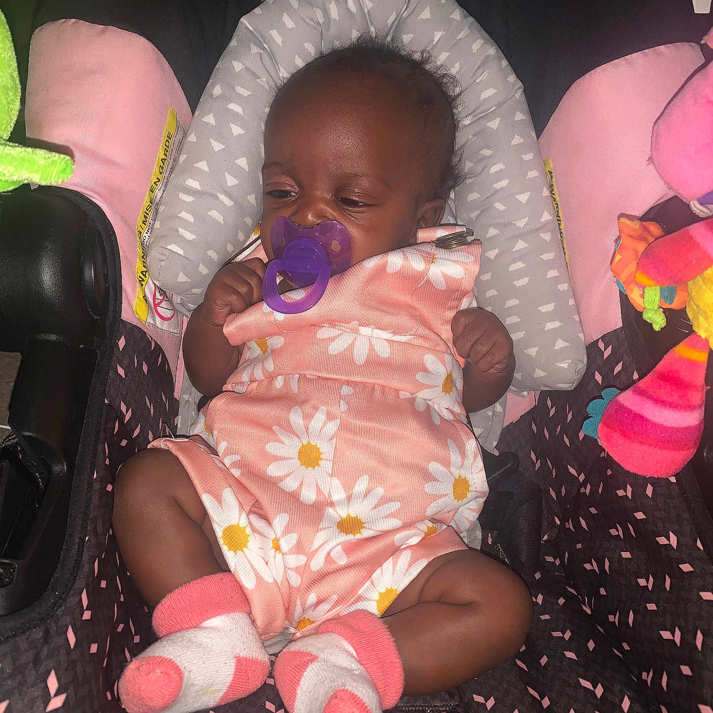 Khalani Cunningham joined the competition — help win amazing prizes! baby, car_seat, child, close_up, colorful, cushion, face, floral_pattern, headrest, indoor, infant, pacifier, photograph, pink_outfit, portrait, relaxed, sitting, sleepy, socks, toy