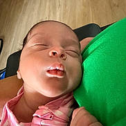 Soul is registered to the contest to win money with this photo: baby, newborn, sleeping, infant, pink_clothing, green_fabric, hand, face, closeup, portrait, peaceful, indoors, wooden_floor, soft_light, skin, head, person, rest, cute, toddler