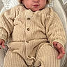baby, infant, knitted_clothing, hat, beige, cushion, baby_seat, cute, small_hands, small_feet, buttoned_suit, indoors, comfortable, child, portrait, expression, cozy, warm_clothing, resting, newborn