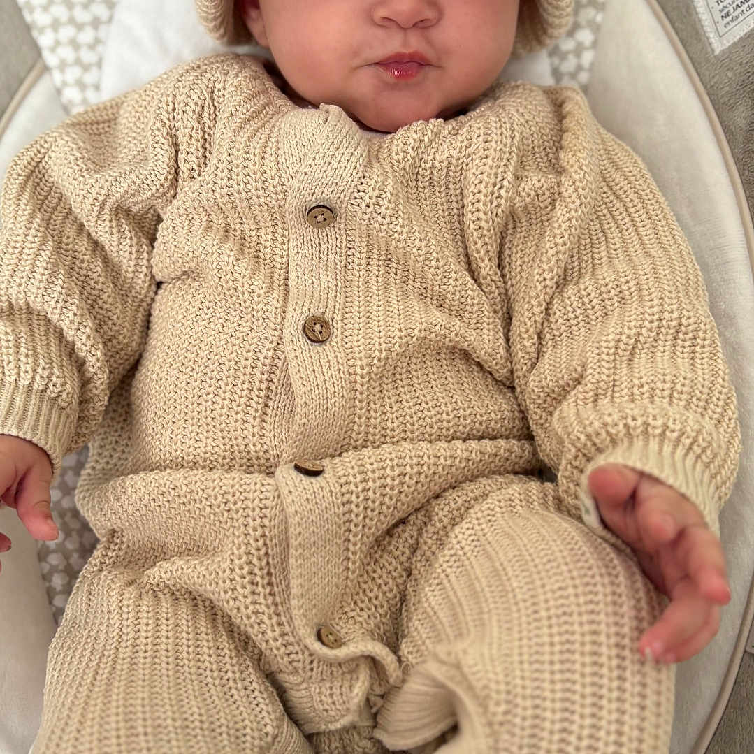 Elma a rejoint le concours — aidez-le/la à gagner de superbes lots ! baby, infant, knitted_clothing, hat, beige, cushion, baby_seat, cute, small_hands, small_feet, buttoned_suit, indoors, comfortable, child, portrait, expression, cozy, warm_clothing, resting, newborn