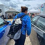 Javel participe au concours pour gagner de l'argent avec cette photo : animal, backpack, black_car, blue_car, blue_sweatshirt, car, casual_clothing, cloudy_sky, daytime, dog, event, gravel_ground, outdoor, people, person, pet, reflection, side_view, tent, white_dog