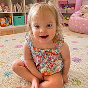Sayler joined the competition — help win amazing prizes! toddler, child, sitting, floral_clothing, carpet, polka_dot, toy_shelf, stuffed_animals, playroom, smiling, indoor, cute, happy, barefoot, young_child, colorful, home, portrait, floor, hair