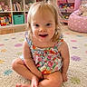 toddler, child, sitting, floral_clothing, carpet, polka_dot, toy_shelf, stuffed_animals, playroom, smiling, indoor, cute, happy, barefoot, young_child, colorful, home, portrait, floor, hair