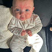 Hallie joined the competition — help win amazing prizes! baby, infant, blue_eyes, onesie, clothing, couch, blanket, indoor, child, person, cute, face, expression, sitting, hands, soft_lighting, texture, furniture, portrait, young