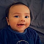 baby, smiling, infant, face, eyes, clothing, blue_outfit, dog_cartoon, hand, blanket, background, cute, happy, portrait, lying_down, young_child, indoor, skin, head, expression