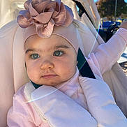 Leya is registered to the contest to win money with this photo: baby, child, stroller, headband, flower, pink_clothing, outdoor, sunlight, lens_flare, face, portrait, infant, cute, soft_tones, seatbelt, happy, daylight, person, young_child, closeup