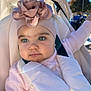 baby, child, stroller, headband, flower, pink_clothing, outdoor, sunlight, lens_flare, face, portrait, infant, cute, soft_tones, seatbelt, happy, daylight, person, young_child, closeup