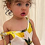 toddler, child, curly_hair, blue_eyes, lemon_print, dress, earring, indoor, curtain, skin, expression, standing, clothing, portrait, young_child, cute, person, fashion, summer_outfit, pom_pom