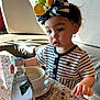 toddler, child, striped_clothing, headband, lemon_accessory, table, marble_table, bottle, water_bottle, cup, earrings, indoor, cafe, curious, sitting, portrait, natural_light, shadow, face, expression